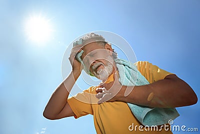 Senior man with towel suffering from heat stroke outdoors, low angle view Stock Photo