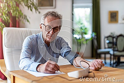 Senior man using medical device to measure blood pressure Stock Photo