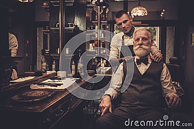 Senior man visiting hairstylist in barber shop. Stock Photo