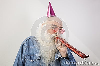 Senior man wearing party hat while blowing horn against gray background Stock Photo