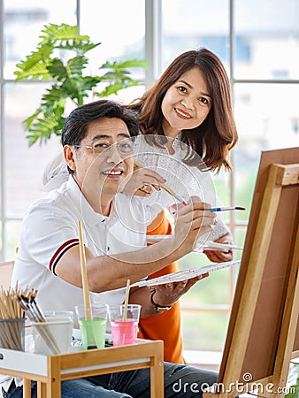 Senior man and woman couple, husband and wife, painting image together in home gallery with warm and happy circumstance. Idea for Stock Photo