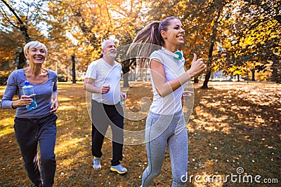 Senior man and woman and young female instructor workout on fresh air. Stock Photo