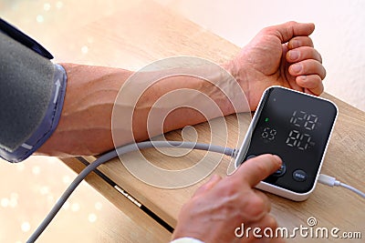 Senior man working with blood pressure machine at home to check his health, self-management, senior health assessment, Stock Photo