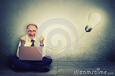 Senior man working on computer with light bulb plugged in it Stock Photo
