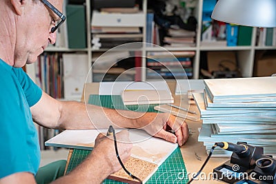 Senior man working with the pyrographer burning the wood making artwork craft in his art studio. Stock Photo