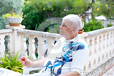 Senior man of 60 years drinking glass of rose wine on vacations. Retired man enjoying warm summer evening Stock Photo