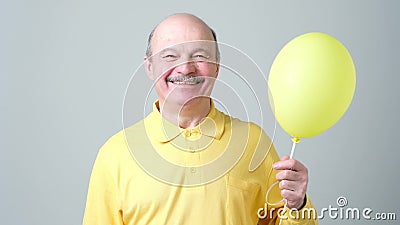 Senior man with yellow balloon with helium in hand Stock Photo