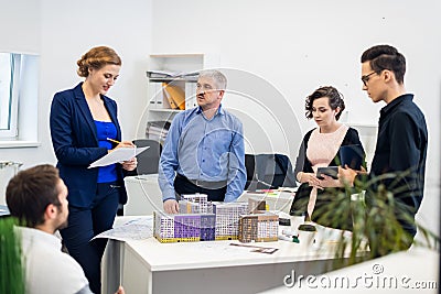 A senior manager holding a meeting with his young team, giving directions, answering questions Stock Photo