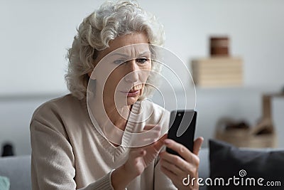 Senior mature retired woman reading unpleasant news in social media. Stock Photo