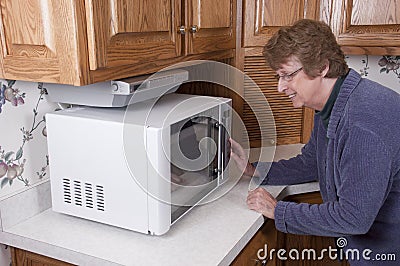 Senior Mature Woman Cooking Microwave Oven Kitchen Stock Photo