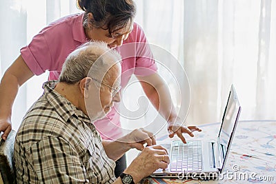 Senior man and his caregiver with laptop at home spending time togheter Stock Photo
