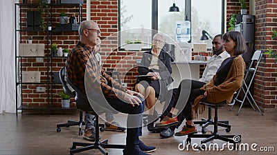 Senior man making confession in front of people and therapist at aa group meeting Stock Photo