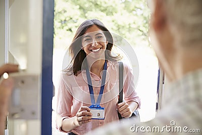 Senior man opening front door to young woman showing ID card Stock Photo