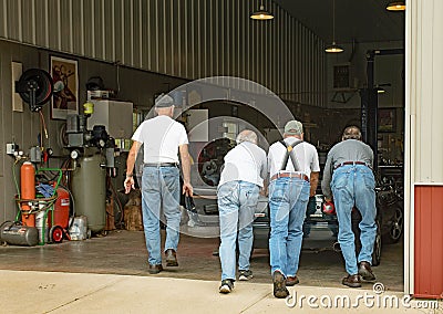 Senior Men Pushing Stalled Car into Garage Editorial Stock Photo