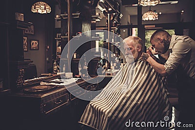 Senior man visiting hairstylist in barber shop. Stock Photo
