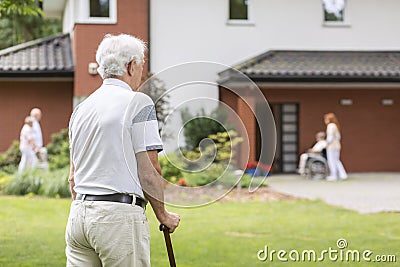 Senior man with walking stick during stay in a nursing house. Bl Stock Photo