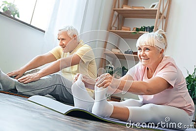 Senior couple doing yoga together at home health care legs stretching Stock Photo