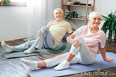 Senior couple doing yoga together at home health care leg stretching Stock Photo