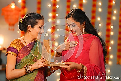 Senior mother giving jewelry necklace gift to daughter at diwali festive celebration at home - concept of special Stock Photo