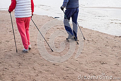 Senior nordic pole walker enjoying nice autumn day outdoors, near sea. active elderly man and woman wearing sport Stock Photo