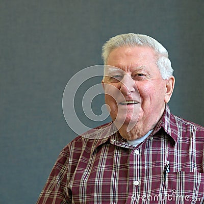 Senior octogenarian old man in plaid with gray background Stock Photo