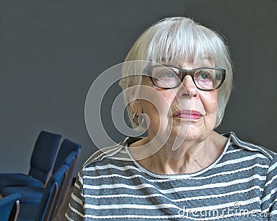 Senior octogenarian woman in striped top with gray background Stock Photo