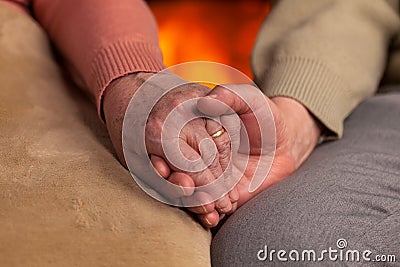 Senior old hands holding in front of fireplace Stock Photo