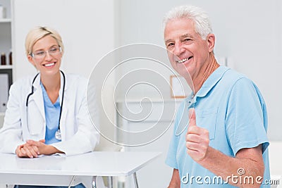 Senior patient gesturing thumbs up while doctor looking at him Stock Photo