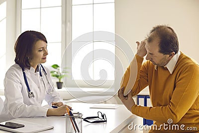 Senior patient visiting clinic and telling general practitioner about his elbow pain Stock Photo