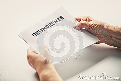 Senior or pensioner holding a letter with german word grundrente, basic pension Stock Photo