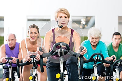 Senior people in gym spinning on fitness bike Stock Photo