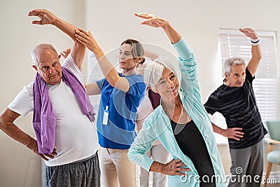 Senior people stretching with trainer at retirement community Stock Photo