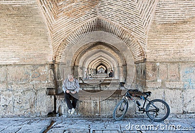 Senior rider reading a book in calmness, under the stone bridge Editorial Stock Photo