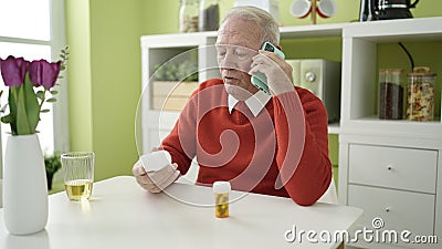 senior speaking on the phone with doctor holding pills at home Stock Photo