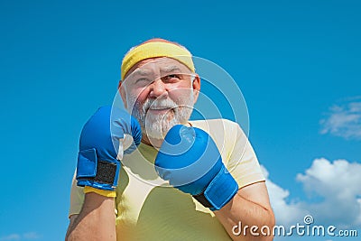 Senior sportive man in boxing stance doing exercises with boxing gloves. Healthy fighter senior old man boxing gloves Stock Photo