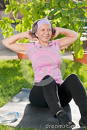 Senior sportive woman doing sit-ups sunny day Stock Photo