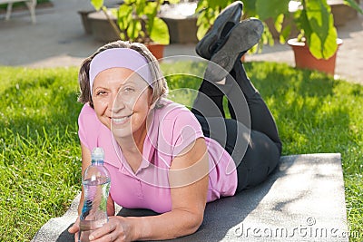 Senior sportive woman lying on mat sunny Stock Photo