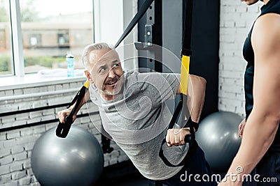 senior sportsman training with trx resistance bands with trainer Stock Photo