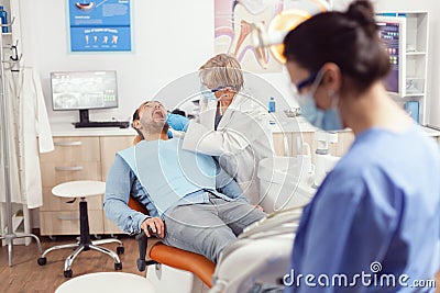 Senior stomatologist holding sterilized dental tools talking with sick patient Stock Photo