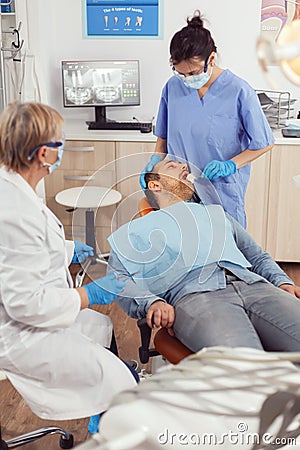 Senior stomatologist woman preparing for surgery putting implant to sick Stock Photo