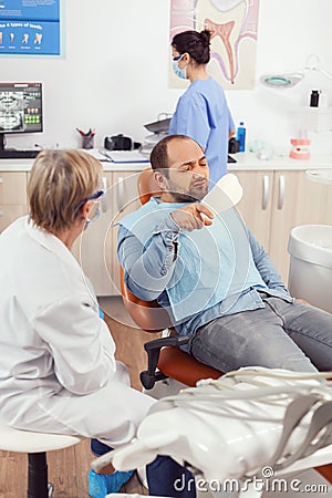 Senior stomatologist woman finishing dental surgery for man patient Stock Photo