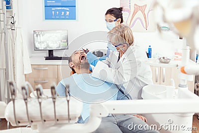 Senior stomatologist woman with protection face mask performing dental inspection Stock Photo