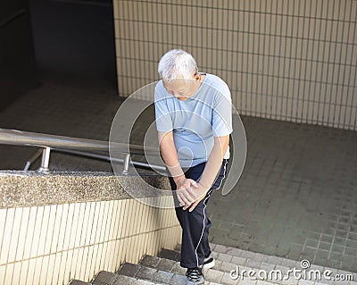 senior Suffering from knee Pain on stair Stock Photo