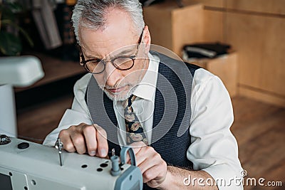 senior tailor threading needle of sewing machine Stock Photo