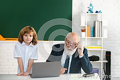 Senior teacher and pupil in classroom. Education concept. Boy elementary school. Old and Young. Grandfather and child Stock Photo