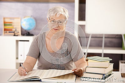 Senior teacher in school searching in a book Stock Photo