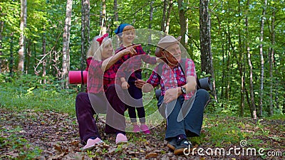 Senior tourists grandmother, grandfather, granddaughter kid talking, sitting with backpacks in wood Stock Photo