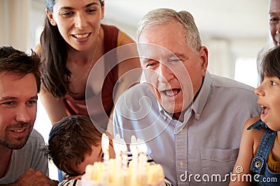 Senior white man celebrating with his family blowing out the candles on birthday cake, close up Stock Photo