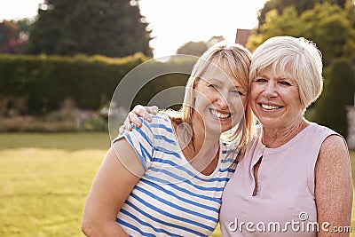 Senior woman and adult daughter embracing in garden Stock Photo