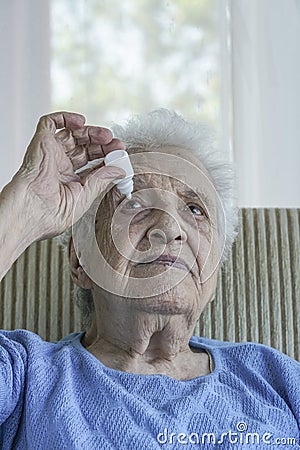 Senior woman applying eye drop on her eye Stock Photo